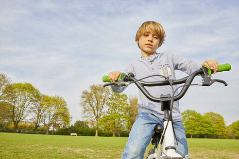 Brunette boy riding his BMX bike in a park. - CUF55576