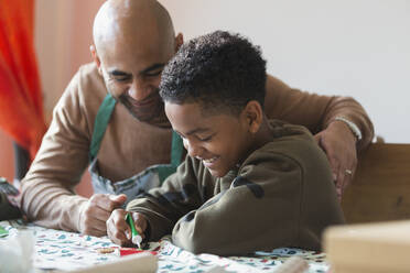 Glücklicher Vater und Sohn beim Verzieren von Weihnachtsplätzchen - CAIF28153