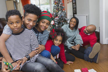 Porträt einer glücklichen Familie, die im Wohnzimmer Weihnachten feiert - CAIF28158