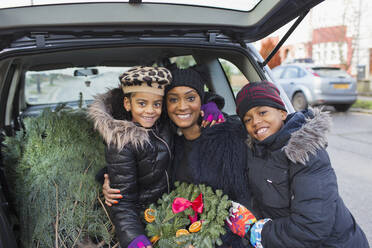 Portrait glückliche Mutter und Kinder mit Weihnachtsbaum und Kranz - CAIF28164