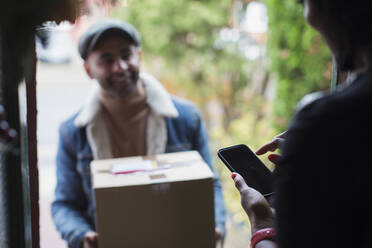 Frau, die an der Eingangstür digital für ein Paket unterschreibt - CAIF28170