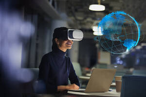 Geschäftsfrau mit Virtual-Reality-Brille schaut auf virtuellen Globus - CAIF28207