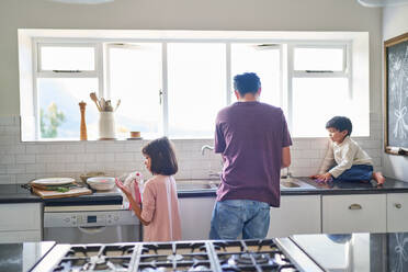 Family doing dishes at kitchen sink - CAIF28231