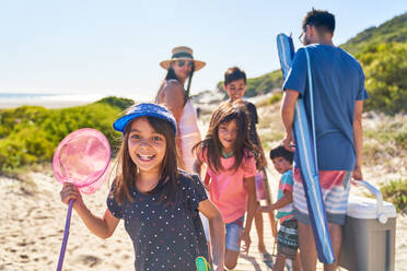 Portrait happy girl with butterfly net on sunny beach with family - CAIF28248