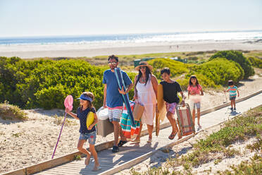 Familie mit Stühlen und Spielzeug auf der sonnigen Strandpromenade - CAIF28252