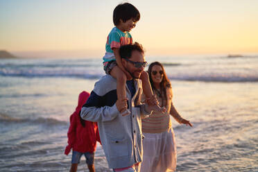 Happy family wading in ocean at sunset - CAIF28255