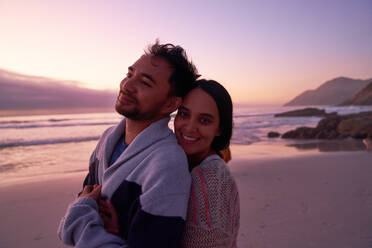 Porträt glückliches zärtliches Paar umarmt am Strand bei Sonnenuntergang - CAIF28259