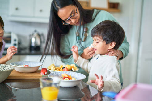 Familie isst Obst in der Küche - CAIF28264