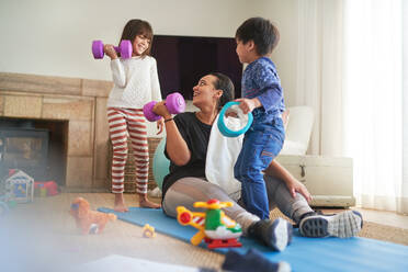 Mutter und Kinder beim Sport im Wohnzimmer - CAIF28272