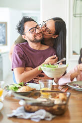 Affectionate couple kissing at dinner table - CAIF28287