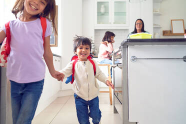 Happy brother and sister holding hands and leaving for school - CAIF28322