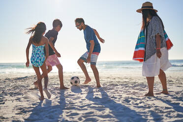 Familie spielt Fußball am sonnigen Strand - CAIF28337