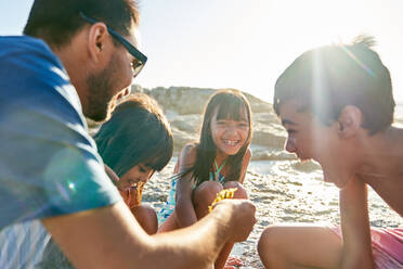 Glückliche Familie spielt am sonnigen Strand - CAIF28340