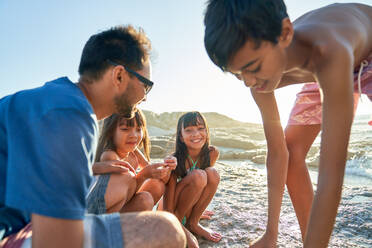 Glückliche Familie spielt am sonnigen Strand - CAIF28345