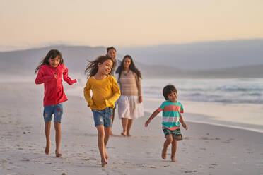 Happy family running on ocean beach - CAIF28354