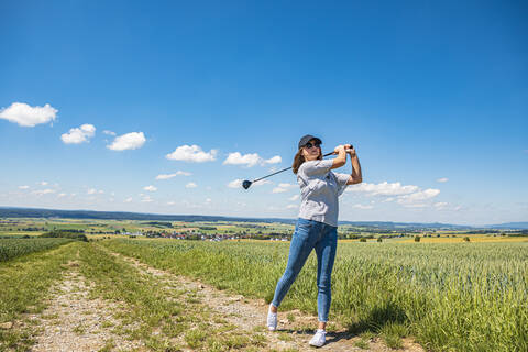 Junge Frau spielt Golf auf dem Lande, lizenzfreies Stockfoto