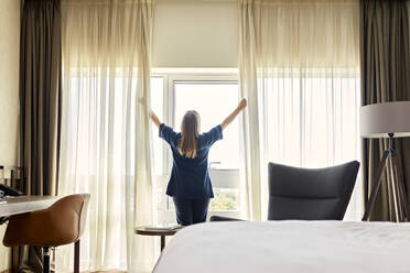 Zimmermädchen öffnet die Vorhänge eines Fensters in einem Hotelzimmer - ZEDF03476