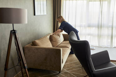 Zimmermädchen ordnet Kissen auf dem Sofa im Zimmer eines Luxushotels - ZEDF03509