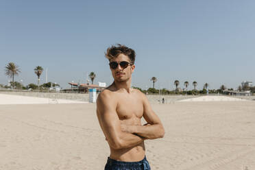 Portrait Of Young Man Wearing Sunglasses Walking At The Beach With
