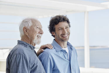 Portrait of confident senior man with adult son at a beach house - RORF02242