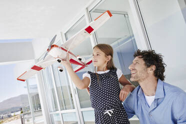 Glücklicher Vater und Tochter spielen mit Modellflugzeug in einer Villa - RORF02244