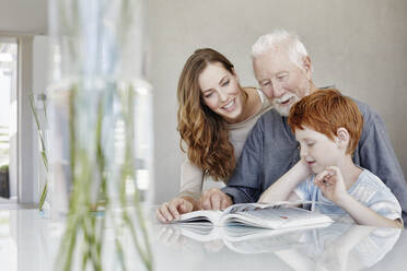 Grandfather, mother and son reading book in a villa together - RORF02253