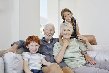 Portrait of happy grandparents with grandchildren on a couch in a villa - RORF02273