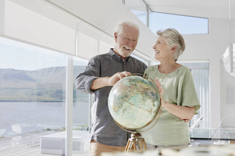 Happy senior couple with globe in a luxury villa stock photo