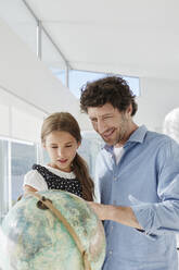 Father and daughter looking at globe in a villa - RORF02303