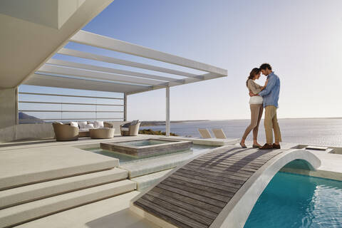 Affectionate couple standing on bridge above a swimming pool stock photo