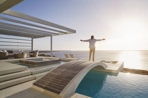 Man standing on bridge above a swimming pool enjoying the view - RORF02330