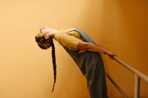 Young woman bending backwards in front of orange wall stock photo