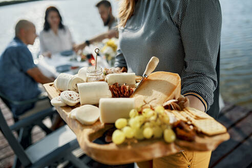 Friends having dinner with a cheese platter at a lake - ZEDF03520