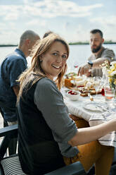 Porträt einer lächelnden Frau beim Abendessen mit Freunden am Seeufer - ZEDF03539