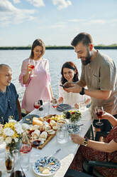 Freunde beim Abendessen an einem See, die ein Smartphone-Foto machen - ZEDF03556