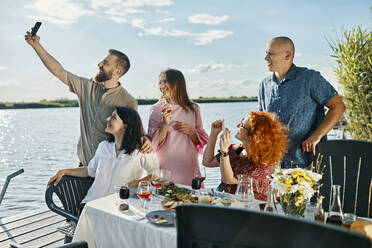 Freunde beim Abendessen an einem See, die ein Selfie machen - ZEDF03562