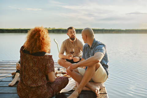 Freunde beim Picknick auf dem Steg eines Sees, lizenzfreies Stockfoto