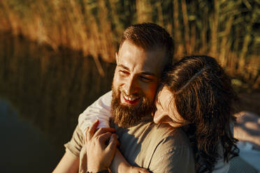 Happy affectionate couple hugging at a lake at sunset - ZEDF03609