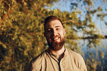 Portrait of smiling man at a lake at sunset - ZEDF03614