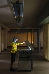 Businesswoman with dyed hair operating photocopier in old abandoned office - JMPF00130