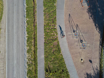 Russland, Tichwin, Mann fährt Fahrrad auf Weg in der Nähe Park Spielplatz, Luftaufnahme - KNTF04848