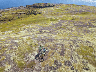 Russland, Gebiet Murmansk, Bezirk Kolsky, Teriberka, Mann mit Fahrrad an der Küste, Luftaufnahme - KNTF04881