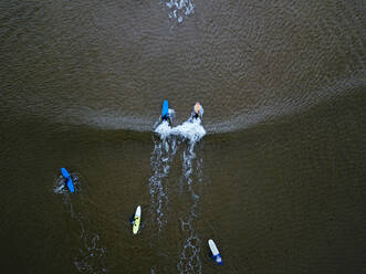 Luftaufnahme von Menschen beim Surfen im braunen Wasser der Barentssee - KNTF04888