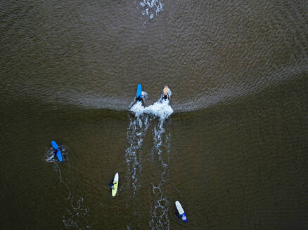 Luftaufnahme von Menschen beim Surfen im braunen Wasser der Barentssee - KNTF04888