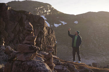 Man taking selfie while standing on rocky mountain at Teriberka, Murmansk Oblast, Russia - KNTF04907