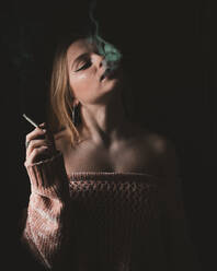 Attractive young sensual woman smoking cigarette on dark background. - ADSF00086