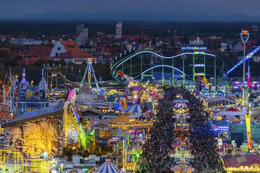 Deutschland, Bayern, München, Drohnenaufnahme von Menschenmassen, die das Oktoberfest in einem großen Vergnügungspark in der Abenddämmerung feiern - MMAF01350