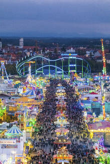 Deutschland, Bayern, München, Drohnenaufnahme von Menschenmassen, die das Oktoberfest in einem großen Vergnügungspark in der Abenddämmerung feiern - MMAF01351