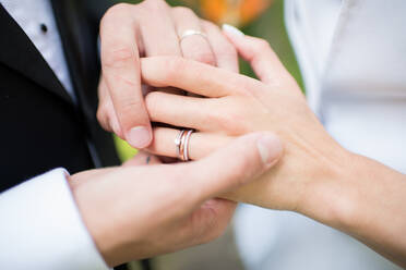 Die Hände des anonymen Bräutigams stecken den Ring an den Finger der nicht erkennbaren Braut während der Hochzeitszeremonie - ADSF00119