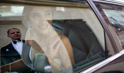 Schöne junge Frau im Hochzeitskleid lächelnd und Blick auf Bräutigam beim Sitzen im Auto - ADSF00124
